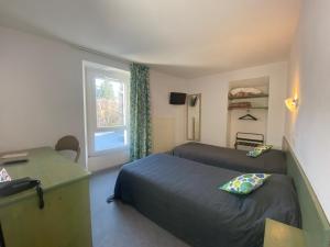 a bedroom with two beds and a desk and a window at HOTEL DE LA GARE in Eygliers