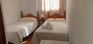 a small bedroom with two beds with white sheets at Alojamiento Rural El Respiro "Brisa" in Benaocaz