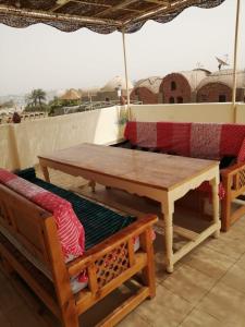 einem Holztisch und Bänken mit einem Regenschirm auf dem Dach in der Unterkunft The Magic of Luxor private studio apartment on the rooftop in Luxor