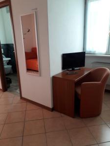 a room with a desk with a television and a chair at albergo del turista srl in Vernasca