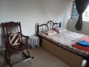 1 dormitorio con cama y mecedora en We have wonderful villa at Shantiniketan. en Santiniketan