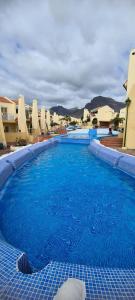 uma grande piscina com água azul em frente aos edifícios em Mare verde 2 em Adeje