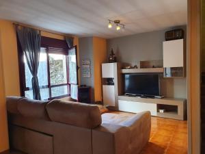 sala de estar con sofá y TV de pantalla plana en Casa rural en la Sierra Norte de Madrid, en Manjirón