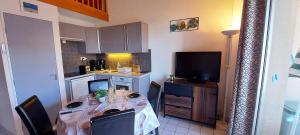 uma pequena cozinha com uma mesa e uma televisão em APPARTEMENT AU CALME AVEC PISCINE ET PARKING dans résidence securisée em Saint-Jean-de-Monts