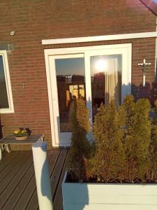 una puerta delantera de una casa con plantas delante en De indiaan, en Noord-Scharwoude