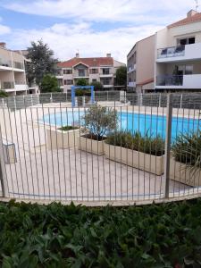 uma cerca em frente a uma piscina em APPARTEMENT AU CALME AVEC PISCINE ET PARKING dans résidence securisée em Saint-Jean-de-Monts