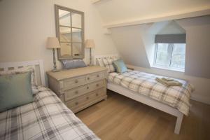 ボートン・オン・ザ・ウォーターにあるCraigmoor Cottageのベッドルーム1室(ベッド2台、ドレッサー、鏡付)