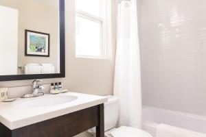 a bathroom with a sink, toilet, mirror and bathtub at Rodd Royalty in Charlottetown