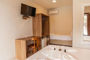 a bedroom with a bed and a tv on the wall at Pousada Algodão da Praia in Araruama