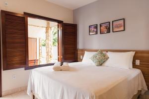 a bedroom with a large white bed with a window at Pousada Algodão da Praia in Araruama