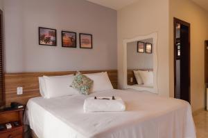 a bedroom with a white bed with a cat on it at Pousada Algodão da Praia in Araruama