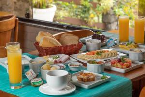 a table with a tray of breakfast foods and orange juice at Pousada Algodão da Praia in Araruama