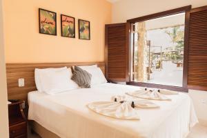 a bedroom with a large white bed with a window at Pousada Algodão da Praia in Araruama