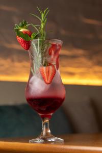 a drink in a glass with strawberries in it at Pousada Algodão da Praia in Araruama