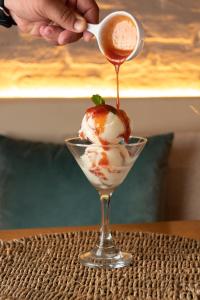 a person is pouring sauce on a ice cream dessert at Pousada Algodão da Praia in Araruama