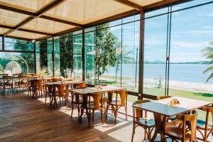 a restaurant with tables and chairs and a view of the ocean at Pousada Algodão da Praia in Araruama