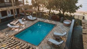 a swimming pool with chairs and a table at Pousada Algodão da Praia in Araruama
