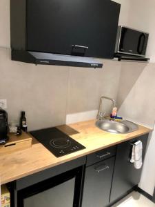 a small kitchen with a sink and a microwave at Sainte Cécile 4 - Studio élégant et central in Vichy