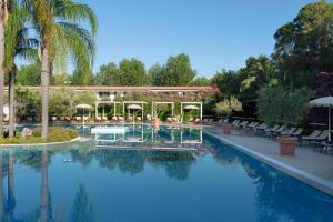 a swimming pool with chairs and a building at Vascellero Club Resort in Cariati