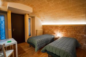 two beds in a room with a stone wall at Grantò B&B in Gravina in Puglia
