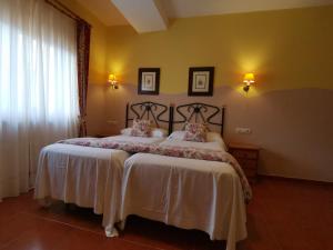 1 dormitorio con 2 camas con sábanas blancas y ventana en Hotel El Angliru, en Soto de Cangas