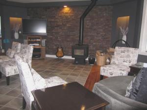 a living room with chairs and a fireplace with a tv at The Bayside Bed and Breakfast in Bareneed