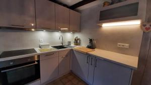 una cocina con armarios blancos y fregadero en Gite Gabrielle en Blaesheim