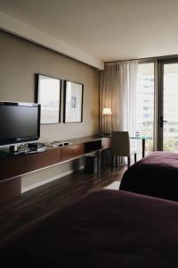 a hotel room with a bed and a desk with a television at Hotel Madero Buenos Aires in Buenos Aires