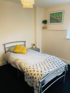 a bedroom with a bed with a yellow pillow on it at Victoria Gardens in Sunderland