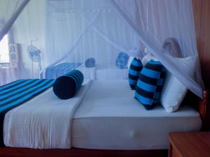 a bedroom with a bed with blue and white pillows at Blue Ribbon Homestay in Ella