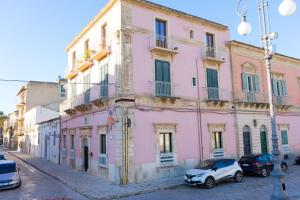 a pink building with cars parked in front of it at Le2Stanze in Vittoria
