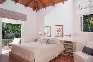 a white bedroom with a bed and a chair at Villa Dafnies in Ágios Prokópios