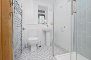 La salle de bains est pourvue de toilettes, d'un lavabo et d'une douche. dans l'établissement Briar Cottage, à Kirk Ireton