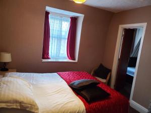 黑潭的住宿－the cumbrian hotel，一间卧室配有一张带红色毯子的床和窗户。
