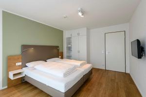 ein Schlafzimmer mit einem Bett mit weißen Laken und einem Fernseher in der Unterkunft Apartmentvilla Anna See Apartmentvilla Anna See 1-11 in Langeoog