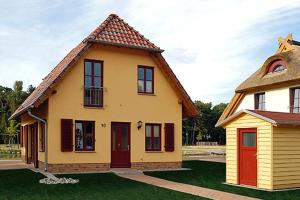 una pequeña casa amarilla con puertas rojas en un patio en Dünenresidenz Glowe Dünenresidenz Glowe A 31, en Klein Gelm