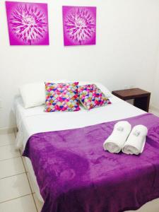 een slaapkamer met een bed met paarse lakens en 2 handdoeken bij Pousada Villa Joia in Barra de São Miguel