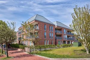 a large red brick building with a metal roof at Apartmentvilla Anna See Apartmentvilla Anna See 1-17 in Langeoog