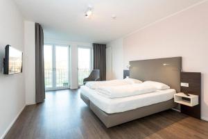 a white bedroom with a large bed and a chair at Apartmentvilla Anna See Apartmentvilla Anna See 2-12 in Langeoog