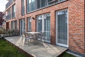 a patio with a table and chairs on a brick building at Apartmentvilla Anna See Apartmentvilla Anna See 1-17 in Langeoog