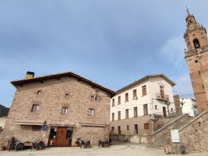 a large stone building with a clock tower next to it at Hotel Rural LATORRIÉN DE ANE in Mues