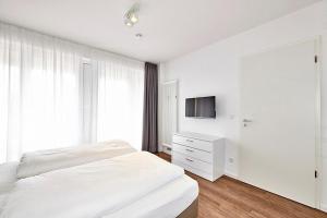 ein weißes Schlafzimmer mit einem Bett und einem Fernseher in der Unterkunft Deichhäuser Anna Küste Deichhäuser Anna Küste 4-14 in Bensersiel