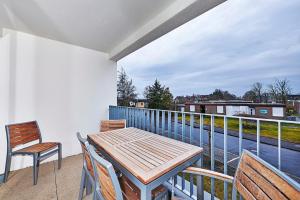 einen Balkon mit einem Holztisch und 2 Stühlen in der Unterkunft Deichhäuser Anna Küste Deichhäuser Anna Küste 4-20 in Bensersiel