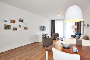 ein weißes Wohnzimmer mit Tisch und Stühlen in der Unterkunft Deichhäuser Anna Küste Deichhäuser Anna Küste 4-10 in Bensersiel