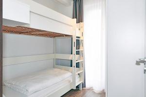 ein Schlafzimmer mit Etagenbetten in einem Zimmer mit Fenster in der Unterkunft Deichhäuser Anna Küste Deichhäuser Anna Küste 4-10 in Bensersiel + 12 Fotos