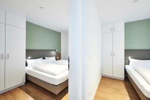 2 Betten in einem Zimmer mit weißen Wänden und weißen Schränken in der Unterkunft Deichhäuser Anna Küste Deichhäuser Anna Küste 4-23 in Bensersiel + 15 Fotos