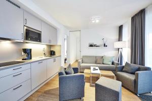 eine Küche und ein Wohnzimmer mit einem Sofa und Stühlen in der Unterkunft Deichhäuser Anna Küste Deichhäuser Anna Küste 4-23 in Bensersiel