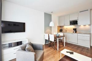 ein Wohnzimmer mit einem Sofa und eine Küche mit einem Tisch in der Unterkunft Deichhäuser Anna Küste Deichhäuser Anna Küste 4-31 in Bensersiel