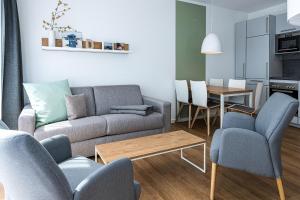 ein Wohnzimmer mit einem Sofa, Stühlen und einem Tisch in der Unterkunft Deichhäuser Anna Küste Deichhäuser Anna Küste 8-24 in Bensersiel