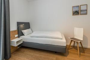 una piccola camera da letto con un letto e una sedia di Deichhäuser Anna Küste Deichhäuser Anna Küste 8-24 a Bensersiel Altre 15 foto